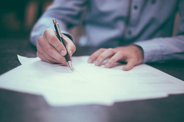 Person filling in a piece of paper with a pen.